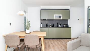 Una cocina moderna con armarios verdes, una mesa de comedor de madera y cuatro sillas.