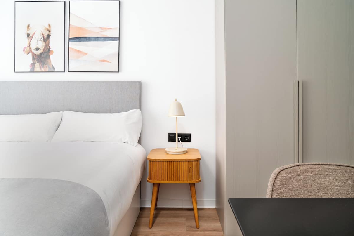 A neatly arranged hotel room with a bed, a bedside table with a lamp, and a chair.