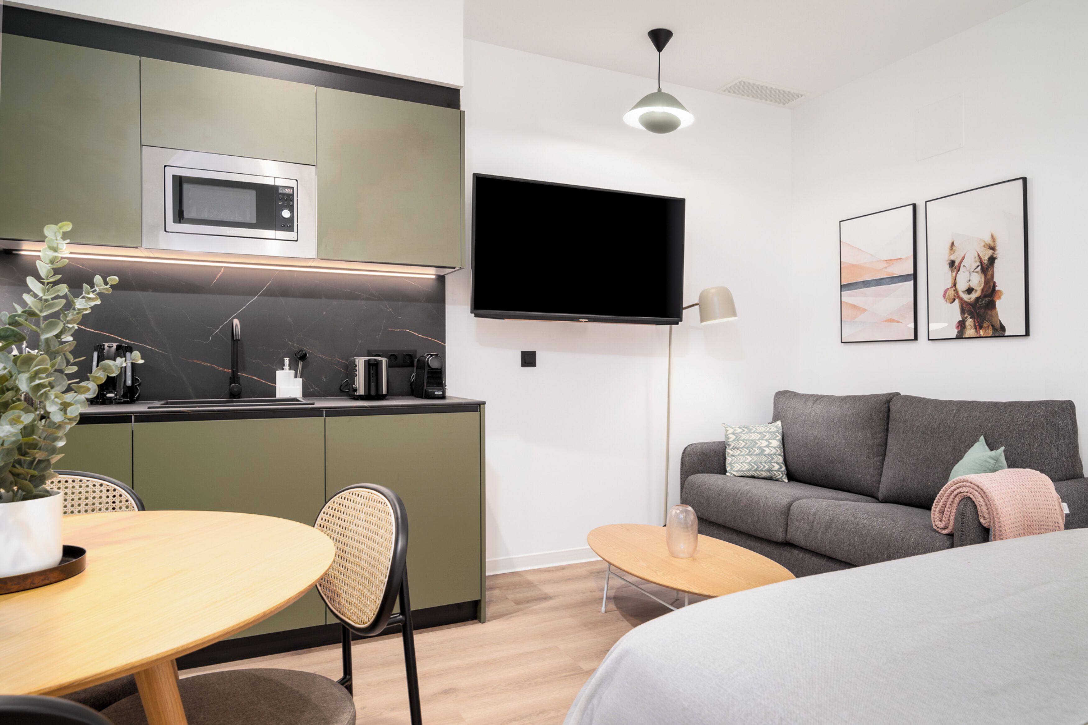 A modern living space with a kitchen, dining area, and a sofa.