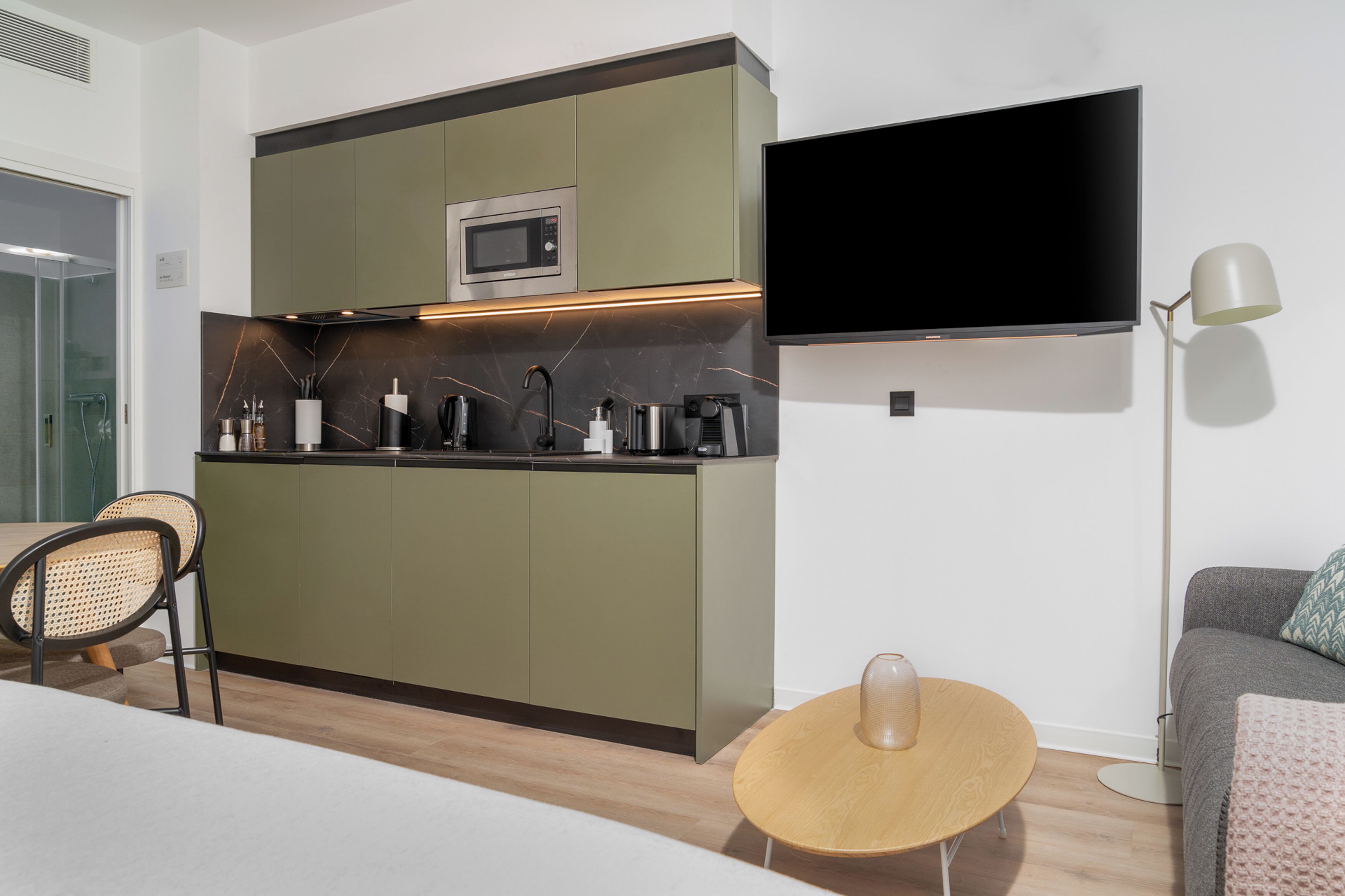 Une cuisine compacte équipée d’un four à micro-ondes, d’un téléviseur à écran plat et d’un coin repas avec une table ronde et des chaises.
