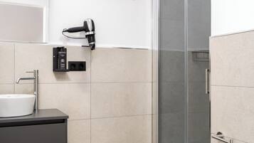 A modern bathroom with a glass shower enclosure, a white sink, and a toilet.