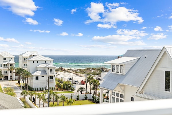 A coastal hotel with multiple white buildings, a beach view, and a clear sky.