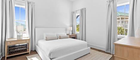 A modern bedroom with a large bed, bedside tables, a nightstand, and a view of the outside.