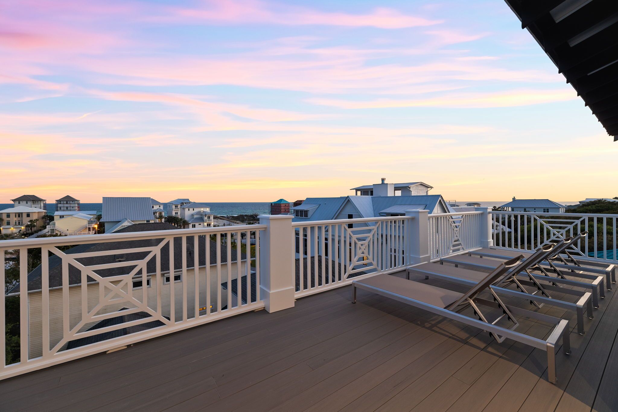 Une terrasse dotée d’une rambarde, offrant une vue sur un quartier résidentiel avec des maisons et un ciel dégagé.