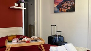 Ein Hotelzimmer mit einem Bett, einem Frühstücksbrett, einem Koffer, einem Gemälde und einer Klimaanlage.