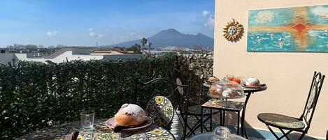 A rooftop terrace with tables, chairs, and a view of a mountain.