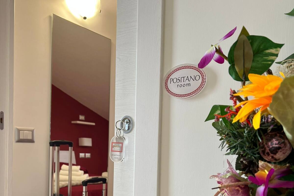 Une chambre d’hôtel avec un lit, une valise et une plante décorative.