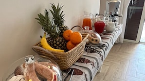Ein Frühstücksbuffet mit Gebäck, Früchten und Getränken auf einer Holzbänkl.