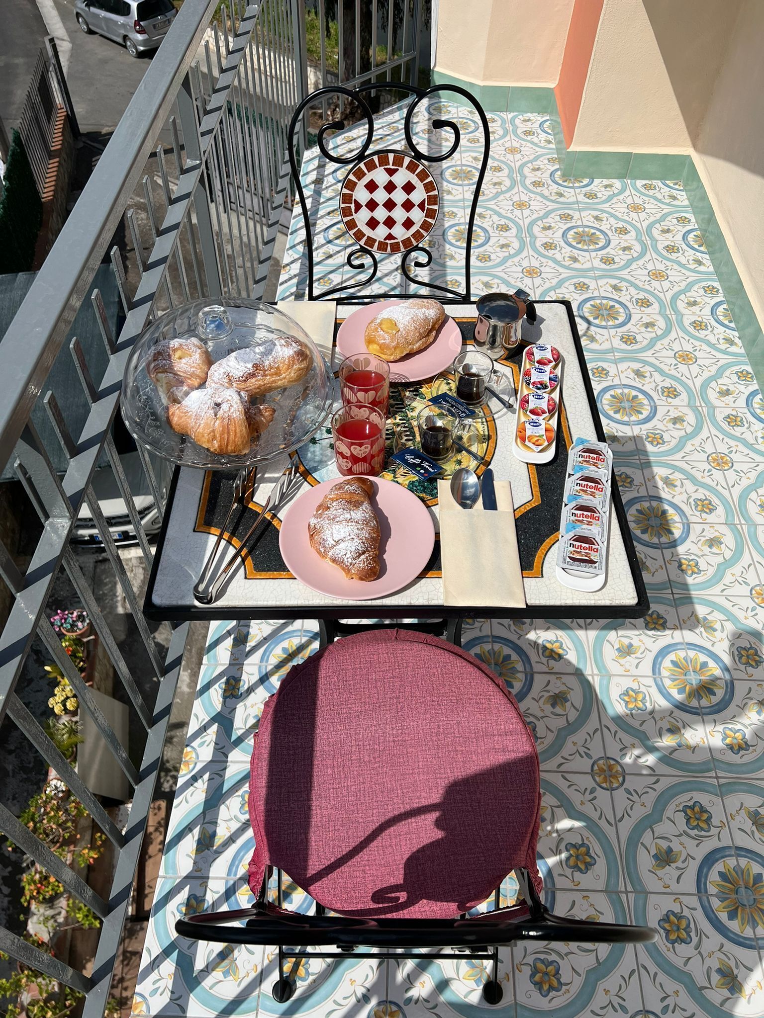 Una mesa dispuesta con pasteles, bebidas y Nutella sobre un suelo de baldosas estampadas.