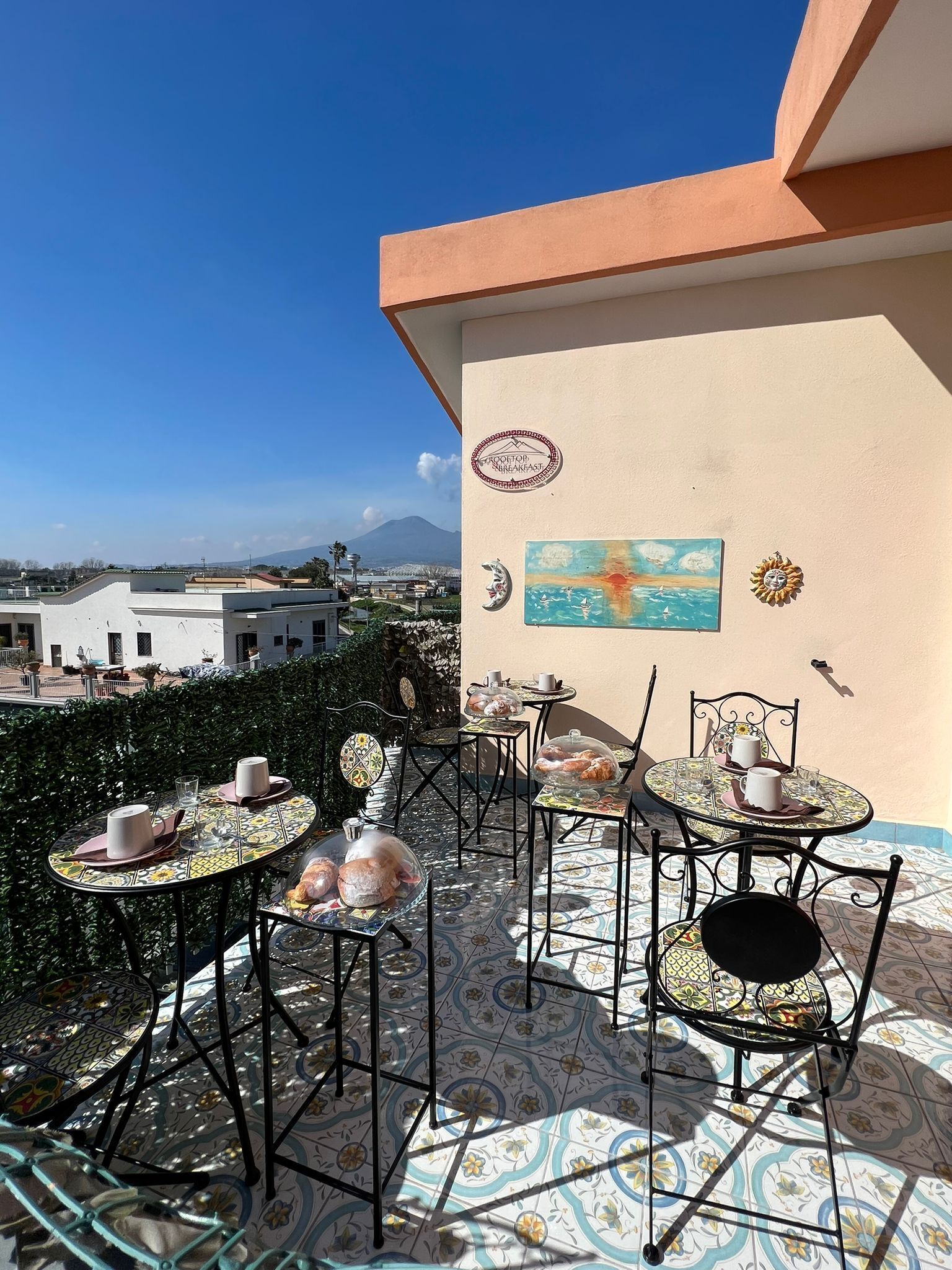 Una terraza con mesas al aire libre, vista de la ciudad y una montaña en la distancia.