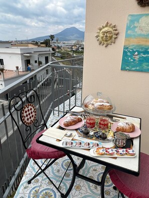 Ein Balkon mit Frühstückstisch, einer verzierten Sonne und Blick auf einen Berg.