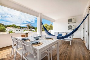 A balcony with a dining table set for four, a hammock, and a view of the city. - Balaia 3BR Sunny Terrace (Albufeira)