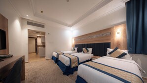 Une chambre d’hôtel avec trois lits, un bureau et une télévision.