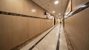 Un couloir d’hôtel avec un sol en marbre, une bordure décorative et une œuvre d’art encadrée accrochée au mur.