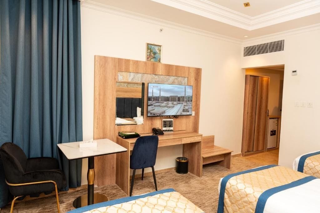 A hotel room with a wooden desk, a television, a bed, and a chair.
