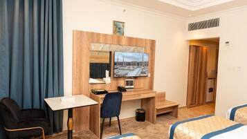 A hotel room with a wooden desk, a television, a bed, and a chair.
