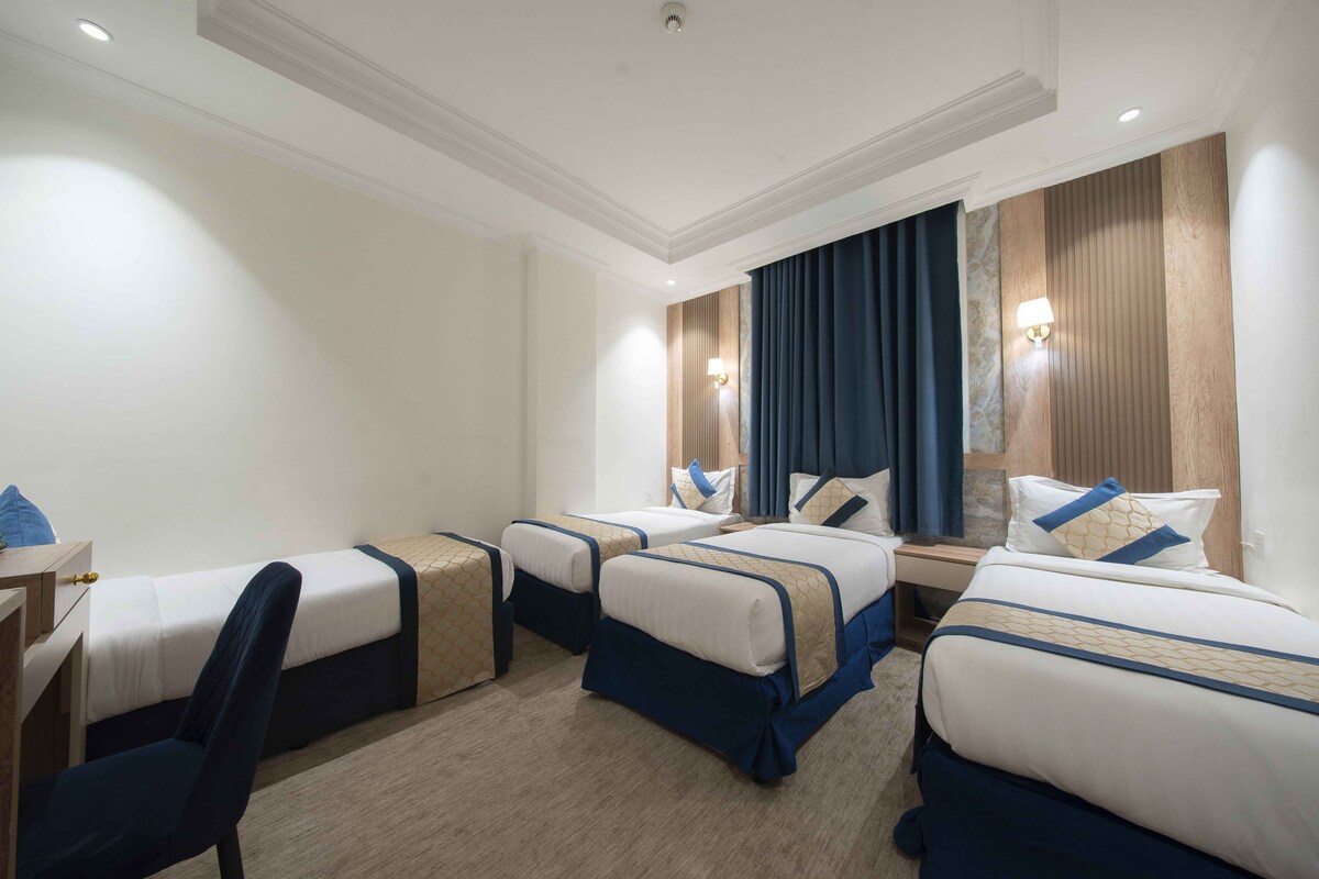 Een hotelkamer met vier eenpersoonsbedden, een bureau en een stoel.