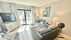 Una sala de estar moderna con un sofá, televisor y un comedor con mesa y sillas.