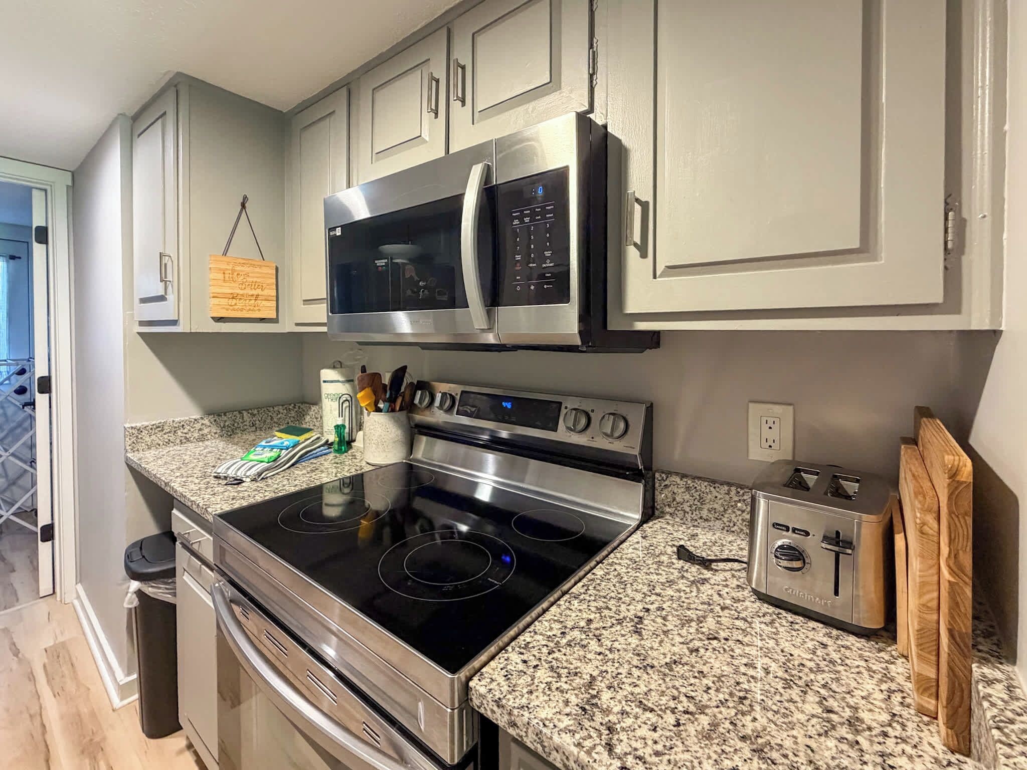A kitchen with stainless steel appliances, granite countertops, and light gray cabinetry.