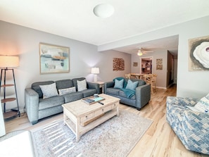 A modern living room with a grey sofa set, a coffee table, and a patterned rug.