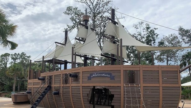 Estructura de juego temática de piratas con diseño de barco, que incluye una escalera y cuerdas.
