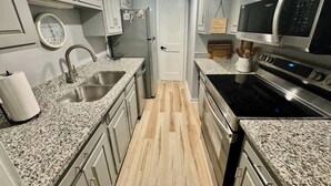 Una cocina con encimeras de granito, electrodomésticos de acero inoxidable y suelo de madera clara.