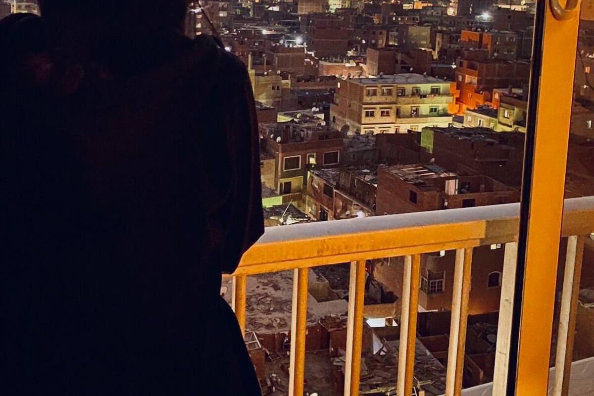 A person overlooking a cityscape with pyramids in the background.