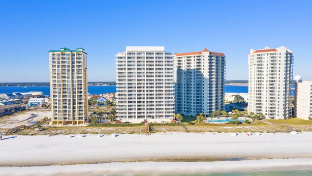 Un hotel sulla spiaggia con diversi edifici a più piani, una spiaggia sabbiosa e una vista libera sull'oceano.