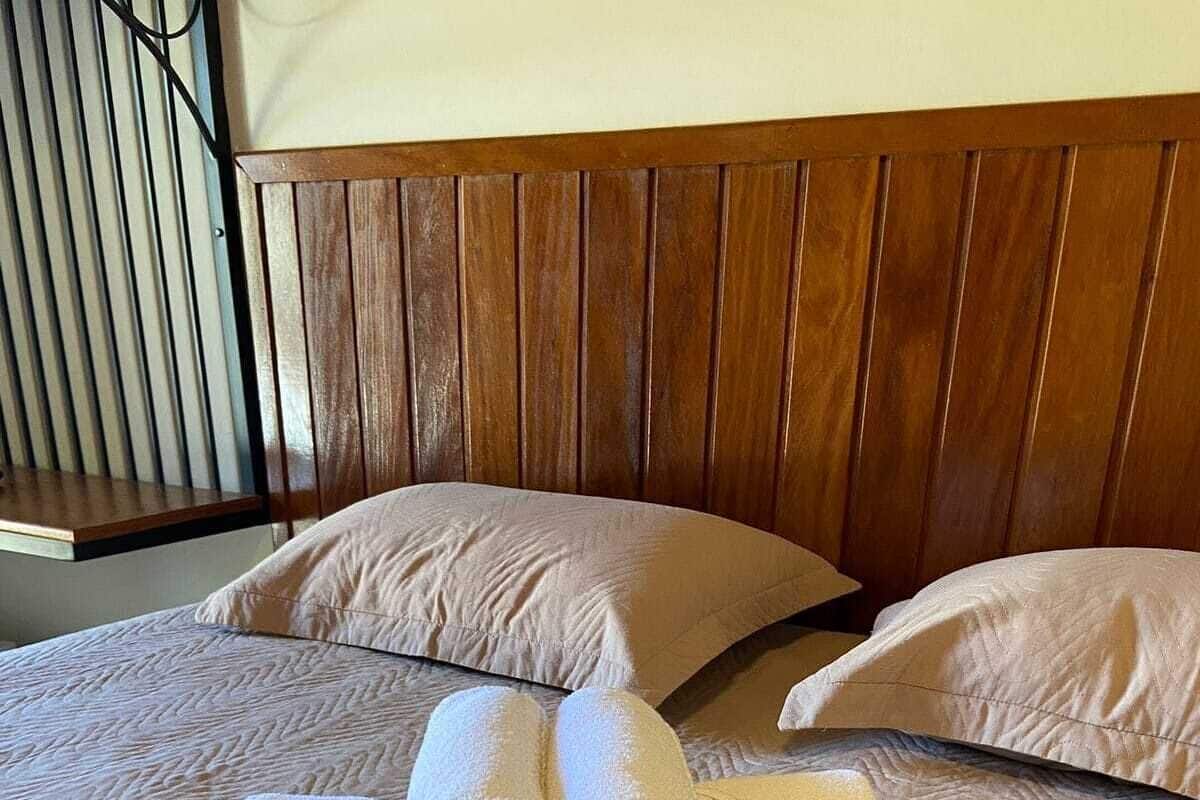 Un lit bien fait, avec deux serviettes enroulées posées sur le dessus, une tête de lit en bois et une couvre-lit à motifs.