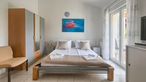 A modern bedroom with a bed, a wardrobe, a bench, and a painting on the wall. - Comfortable Villa Ajda with sea view and heated pool (Pula)