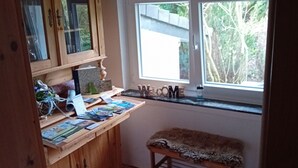 Una habitación con un escritorio de madera, una ventana que da a zonas verdes y un banco.