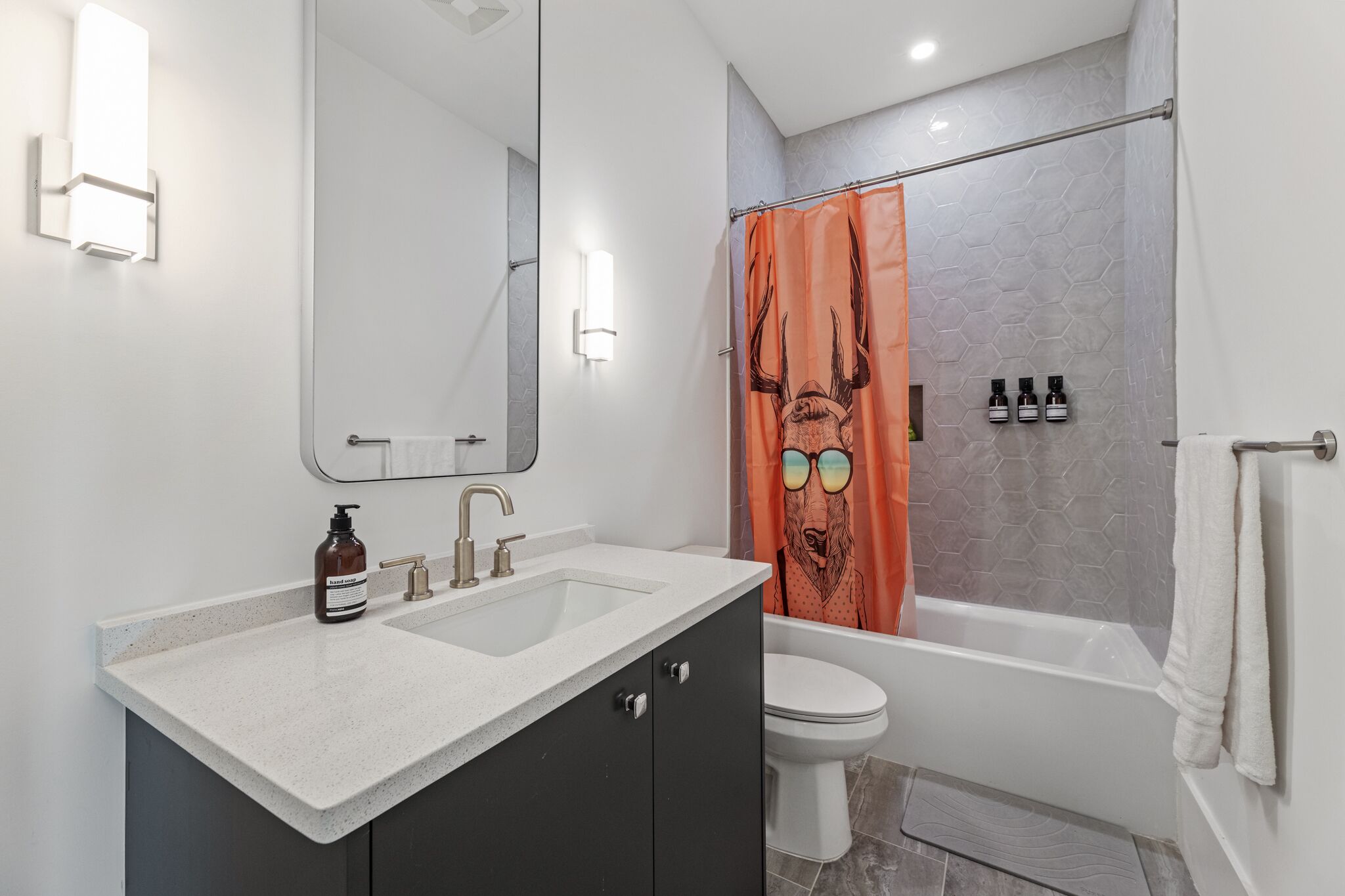 A modern bathroom with a double sink vanity, a toilet, and a bathtub.