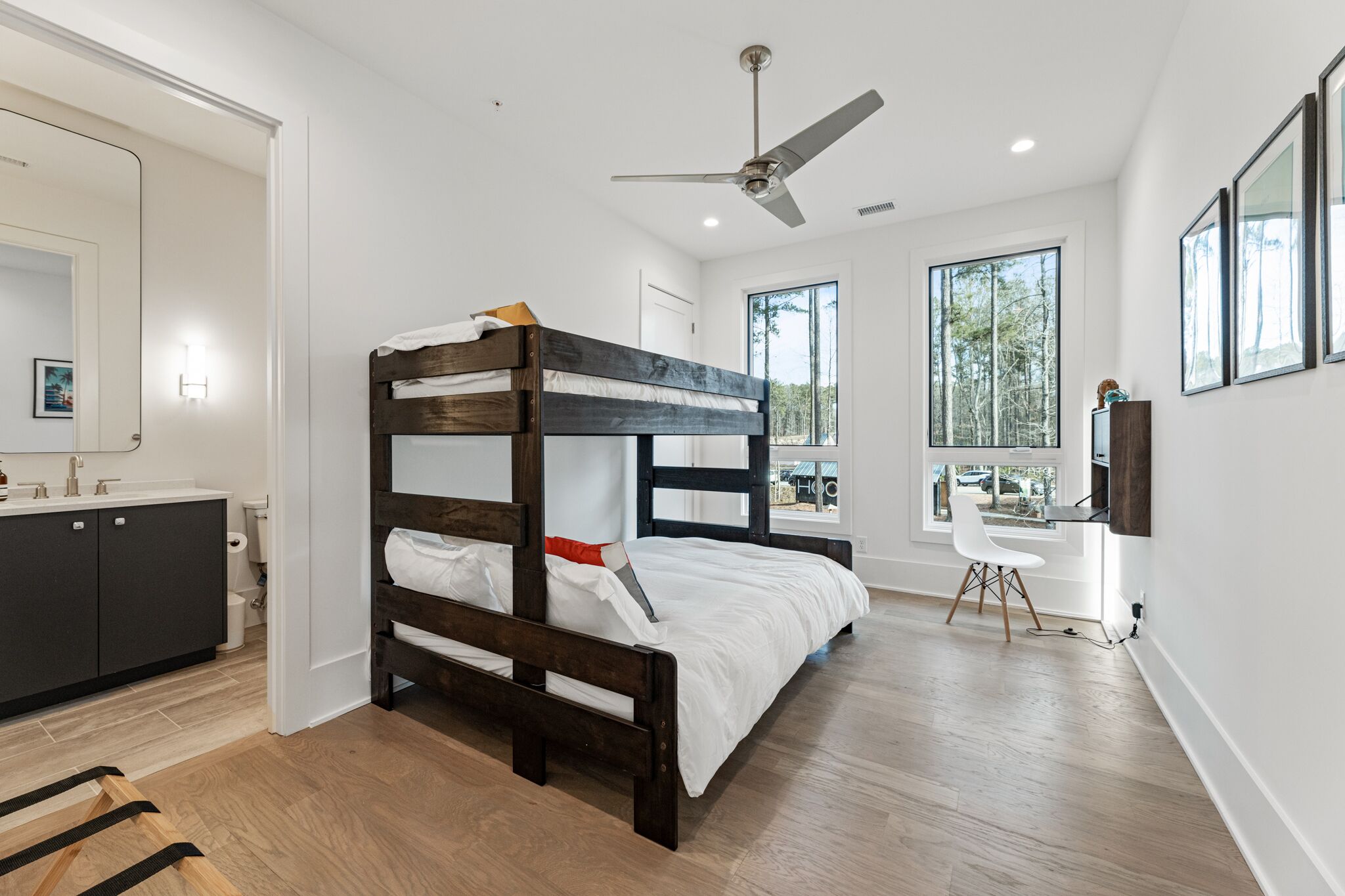 Une chambre moderne avec un lit superposé en bois, un bureau et une grande fenêtre.