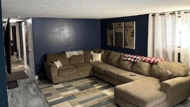 Ein Wohnzimmer mit einer Eckcouch, einem gemusterten Teppich und einer dunkelblauen Wand.