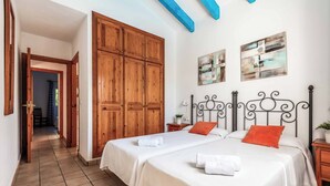 A bedroom with two beds, wooden wardrobe, and artwork on the wall.