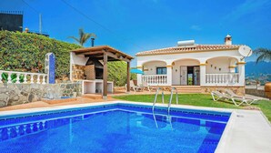 A swimming pool with a clear blue tile, a covered patio, and a house with a tiled roof and white walls. - Villa Los Sanchez - Two Bedroom Villa, Sleeps 4 (Frigiliana)