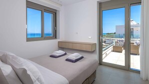 Een slaapkamer met een bed, een raam, een schuifdeur naar een balkon en een houten plank.