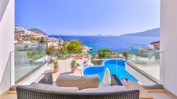 A balcony with a view of a swimming pool and the sea.