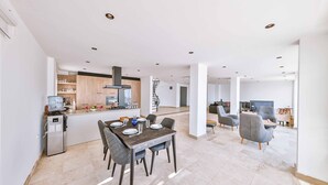 A spacious living area with a dining table, chairs, and a kitchen area with modern appliances.
