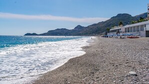 A pebble beach with a building on the right. - Beach House AcquaMarina (Letojanni)