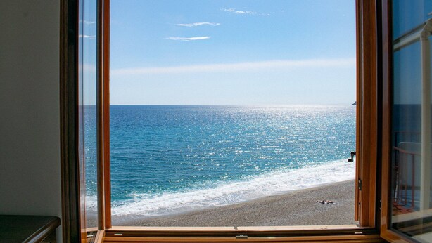 A view from a window overlooking a beach with a clear sky. - Beach House AcquaMarina (Letojanni)