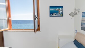 A bedroom with a view of the sea, a bed, a painting, and a wall-mounted lamp. - Beach House AcquaMarina (Letojanni)
