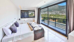 Une chambre moderne avec un grand lit, une salle de bain et un balcon offrant une vue sur la ville.