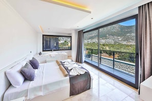 Una camera moderna con un letto grande, un bagno e un balcone vista città.