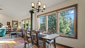A spacious living room with a dining area, large windows, and a chandelier. - Waterfront! New Construction The Resting Place (Sturgeon Bay)