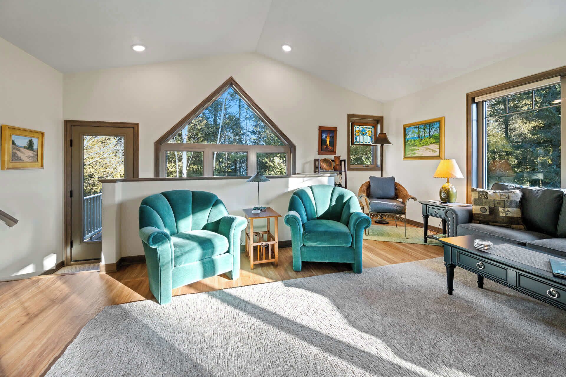 Un salon spacieux avec deux fauteuils turquoise, une table basse en bois et un canapé.