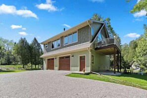 Ett tvåvåningshus med en inglasad veranda, ett garage och en uppfart.
