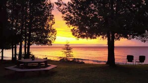 A sunset view with a picnic table and chairs by the water. - Waterfront! New Construction The Resting Place (Sturgeon Bay)