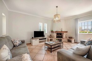 Ein Wohnzimmer mit Kamin, Fernseher und Sofas.