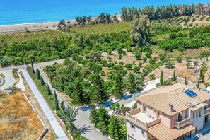 A coastal property with a large building, a paved driveway, and a landscaped area with trees and shrubs. - Villa Vasilissa - Five Bedroom Villa, Sleeps 10 (Agia Marina Chrysochous)